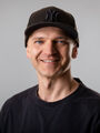 Mitarbeiterfoto: Lächelnder Mann mit Kappe und Pullover